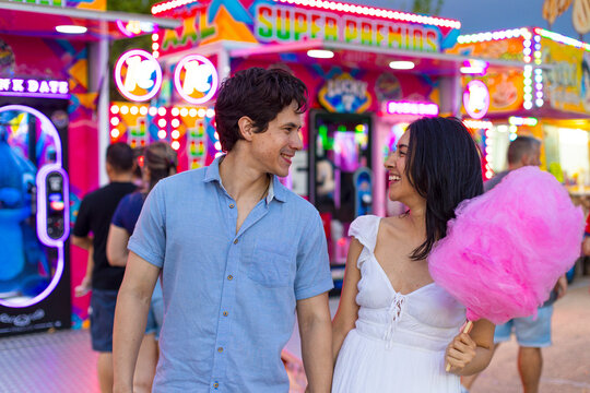 Happy couple enjoying fun fair holding cotton candy