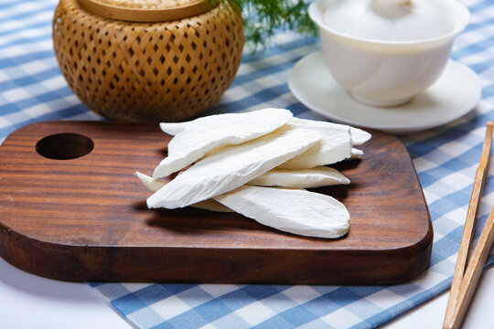Dried Chinese Yam Slices On Wooden Plate With White Tea Set