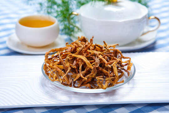 Dried Daylily Flowers On Glass Plate Over Wooden Cutting Board