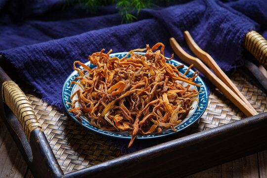 Dried Daylily Flowers On Glass Plate Over Wooden Cutting Board