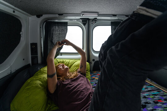 Happy woman waking up and stretching in camper van