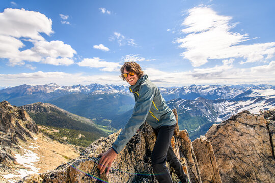 Happy man climbing on a rocky mountain summit on a sunny day