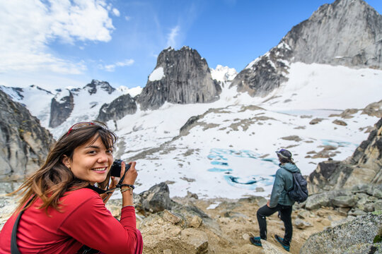 Woman smiles while photographing on a mountain hike
