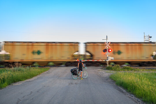 Bike tourer waits for a train at a rural railroad crossing