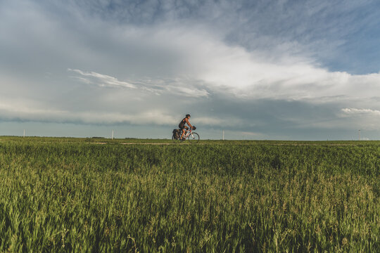 Cyclist riding a touring bike across a vast open prairie