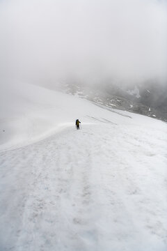 Lone hiker trekking through a foggy snowy mountain landscape