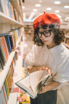 Young woman in a red beret reading in a bookstore