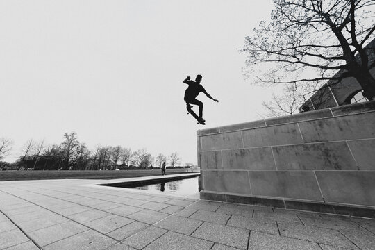Skateboarder launches from a concrete ledge in a public space.