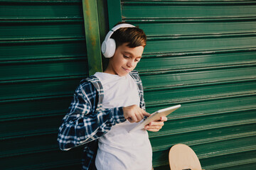 Boy using tablet outdoors while wearing headphones © djile