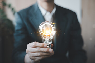 Business innovation concept showing a professional holding a glowing light bulb with gears, symbolizing creativity, technology, ideas, problem solving, innovation and future growth. © Ben_24