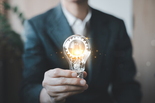 Business innovation concept showing a professional holding a glowing light bulb with gears, symbolizing creativity, technology, ideas, problem solving, innovation and future growth.