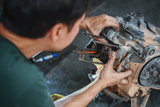 mechanic's hands assembling a piston and piston rings into an engine cylinder block during a motorcycle engine overhaul in a local repair shop.
