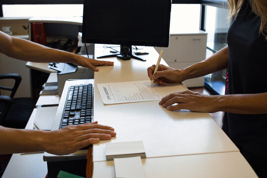 Woman signing a gym membership agreement at the reception desk, close-up of hands starting a new fitness plan and a healthy lifestyle commitment
