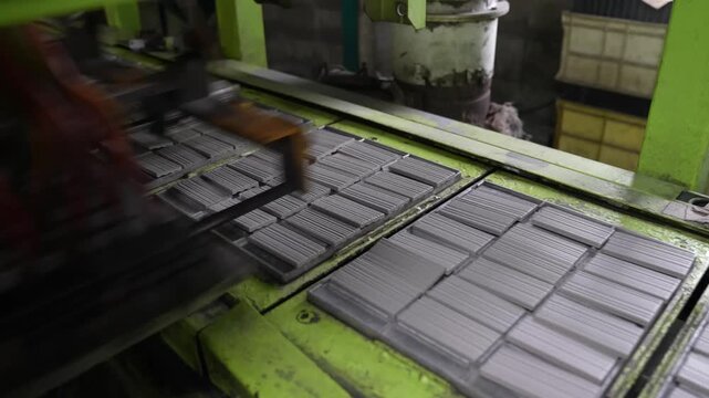Dark grey ceramic tile panels move through a green transfer machine fitted with a multi head gripper