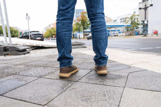 Man standing on wet pavement in a city street on a cloudy day