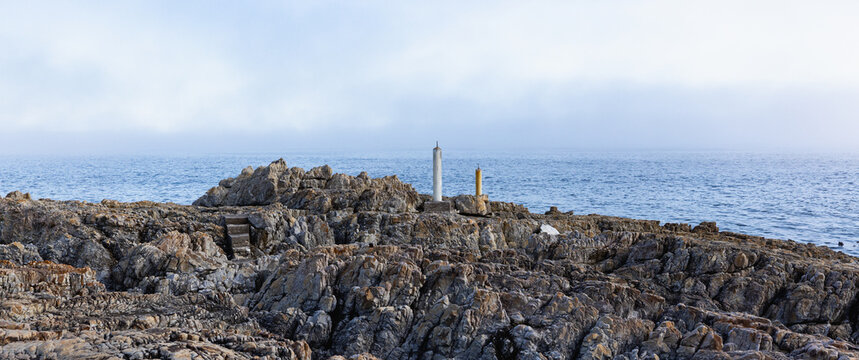 fog bank and afternoon sunlight over rocky coastline of Hermanus, South Africa