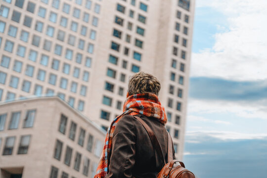 Person looks up at tall building with modern urban aria