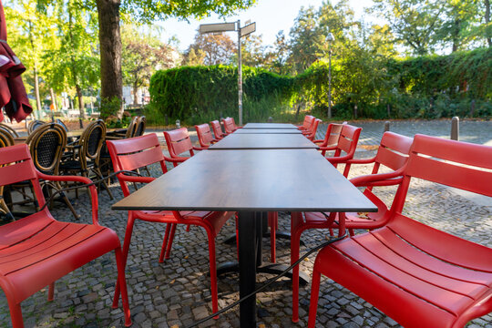 Red chairs and tables set up for dining outside in park during daytime