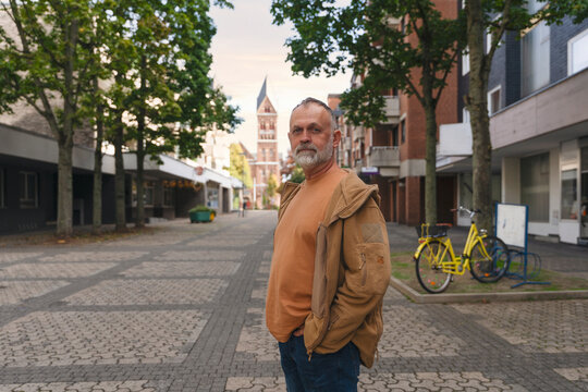 Man standing in an empty street with trees and a building in the