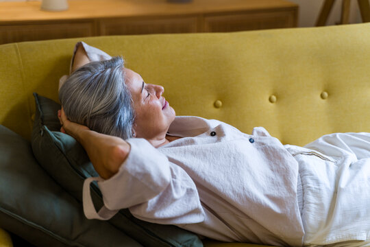 White woman relaxing on a yellow sofa in a calm indoor setting