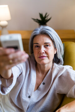 White woman holding remote control in living room setting