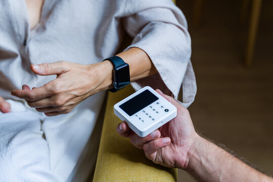 White person wearing smartwatch holding small digital numeric keypad