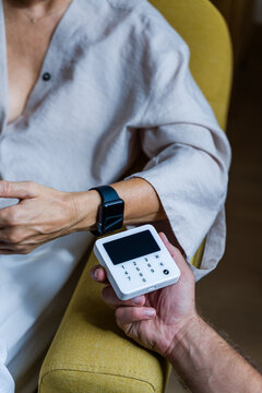 Person using smartwatch for contactless payment on white terminal