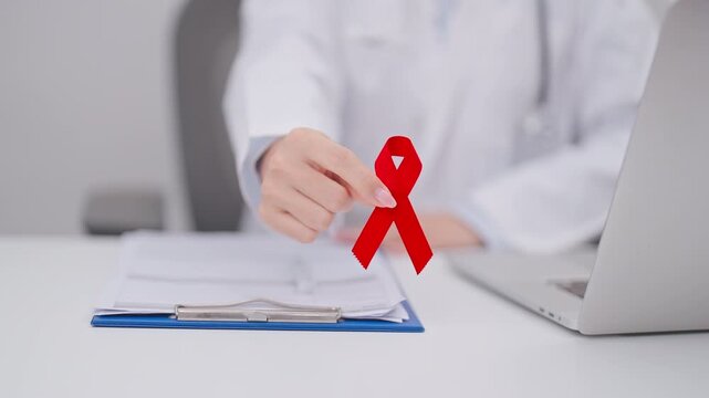 Doctor giving red ribbon to patient for concept of December World Aids Day, MADD, October Red ribbon week, February Heart month, Marfan Syndrome, May Stroke awareness, March world TB Tuberculosis