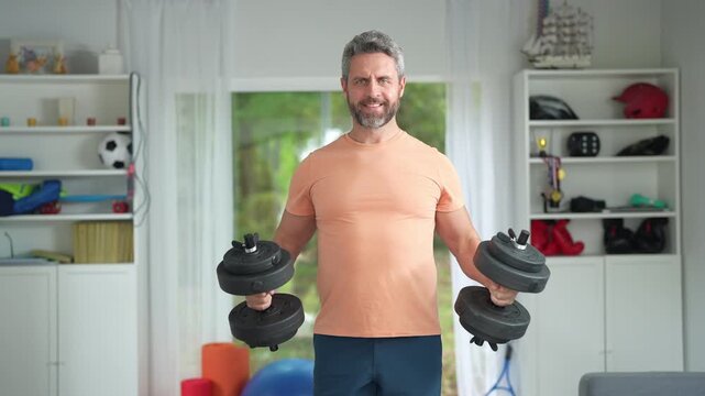 Man lifting dumbbells for strength. Dumbbells workout for home fitness. Man training muscles with weights. Home workout with dumbbells and focus. Fitness man exercising with dumbbells.