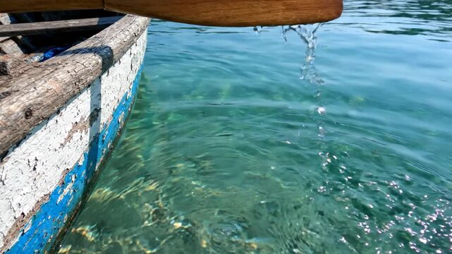 Wooden oar paddling through crystal clear turquoise water
