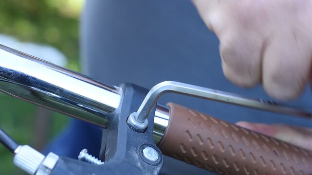 A man is tightening a bolt on a bicycle handlebar with a hex key.