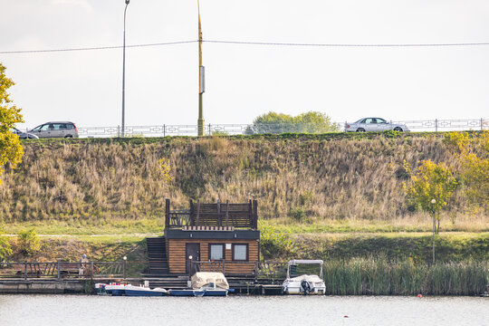 Wooden boathouse and pier on riverbank with roadway above