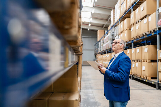 Male manager inspecting inventory with a tablet in a warehouse