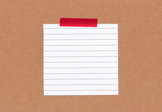 A blank white lined paper is taped to a brown cardboard background