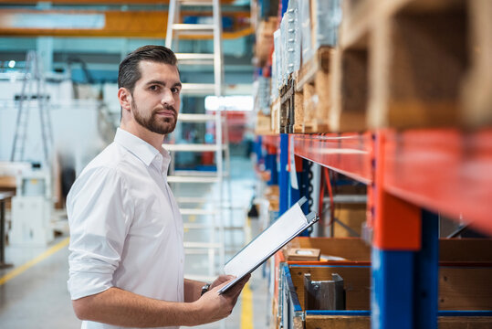 A male manager inspects inventory in a warehouse