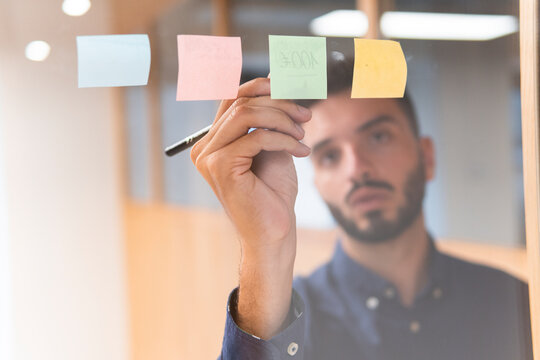 Young businessman writing on adhesive notes