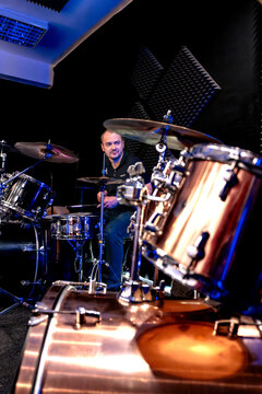 A drummer plays a drum kit in a music studio