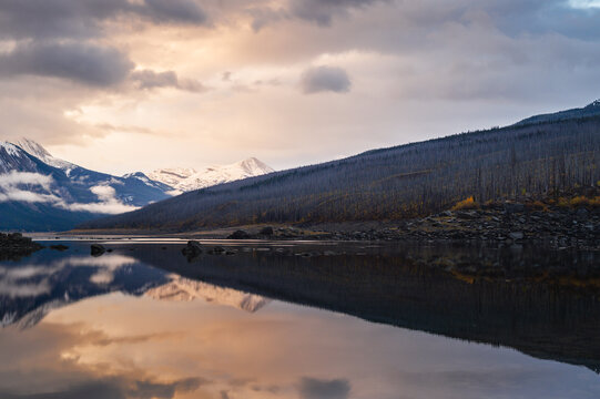Serene lake reflection captures dramatic sunset sky above mountain wilderness in scenic canada providing deep tranquil harmony