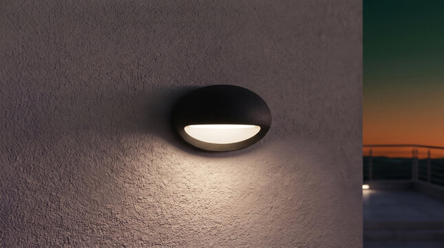 Sleek black oval wall light illuminating a textured stucco house facade at sunset