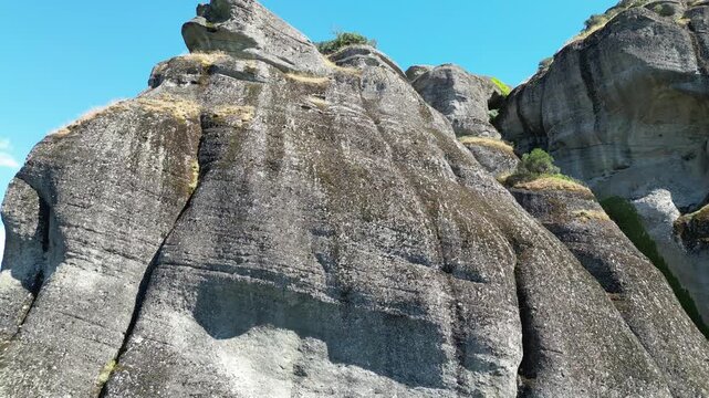 Close up view of ancient grey conglomerate rock formation peaks against clear blue sky in Meteora Thessaly Greece for natural landscape background design.