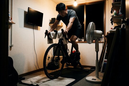 Asian man riding a stationary bicycle trainer indoors