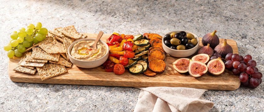 Vegetable grazing board with hummus crackers grapes and figs