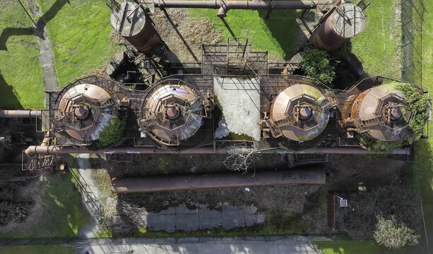 Aerial view of the historic industrial structures at Gas Works Park, featuring rusted metal towers and pipes set against green grass in Seattle, WA, United States.