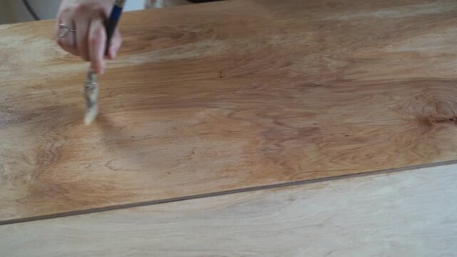 Home renovation: applying protective varnish to a wooden table with a brush