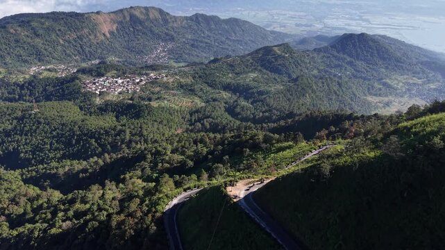 Drone aerial footage of motorcycle riders navigating scenic winding mountain roads on Mount Telomoyo in Central Java, Indonesia, showcasing adventure travel.