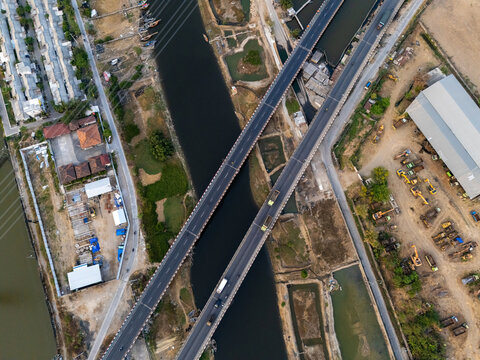 Aerial view of two parallel bridges crossing a river, with construction equipment and industrial buildings nearby, Semarang, Central Java, Indonesia.