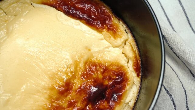 Freshly baked low-fat cottage cheese casserole with a golden caramelized crust in a round metal baking pan on a striped kitchen towel, healthy homemade diet dessert. High quality 4k footage