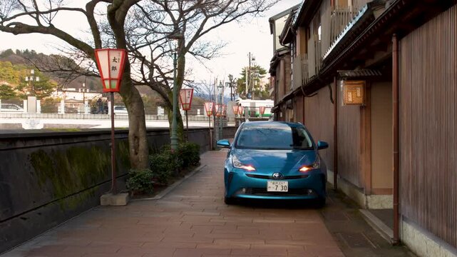 Blue Car Driving Slowly Along Narrow Traditional Japanese Street
