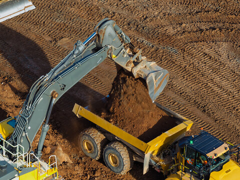 Aerial view of an excavator loading soil into a dump truck at a high speed rail construction site in the United Kingdom.