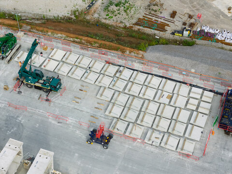 Aerial view of High Speed Rail Construction site featuring a mobile crane and rows of precast concrete segments arranged on a paved surface, United Kingdom.